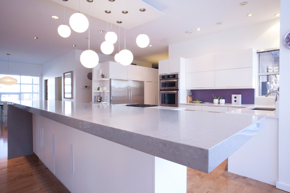 This is an example of a modern eat-in kitchen in Other with an undermount sink, flat-panel cabinets, white cabinets, quartz benchtops, stainless steel appliances, medium hardwood floors and with island.