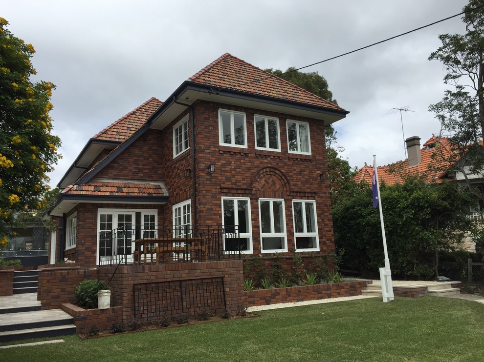 Photo of a large traditional two-storey brick red house exterior in Sydney with a hip roof and a tile roof.