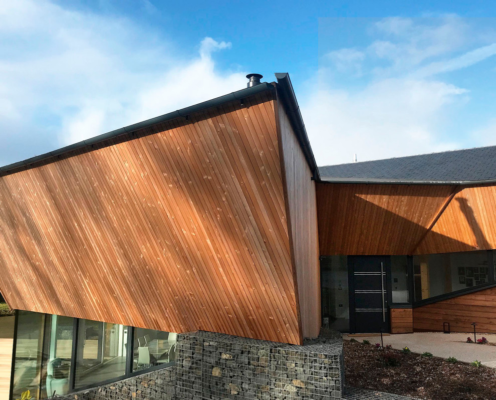Photo of a large contemporary two-storey house exterior in Sussex with wood siding.