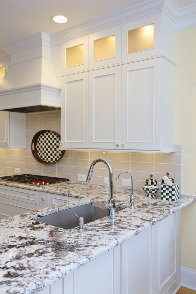 Inspiration for a mid-sized transitional l-shaped eat-in kitchen in Raleigh with an undermount sink, recessed-panel cabinets, white cabinets, granite benchtops, subway tile splashback, black appliances, medium hardwood floors, beige splashback, brown floor and multi-coloured benchtop.