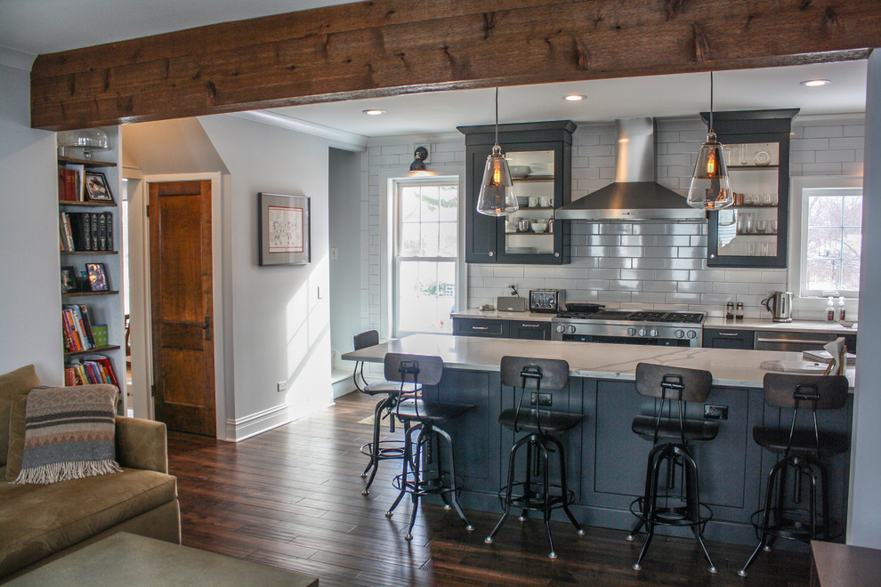 Inspiration for a mid-sized transitional single-wall dark wood floor and brown floor open concept kitchen remodel with a drop-in sink, beaded inset cabinets, black cabinets, granite countertops, gray backsplash, ceramic backsplash, stainless steel appliances, an island and white countertops