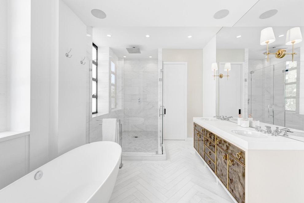 Design ideas for a mid-sized contemporary master bathroom in New York with marble, white walls, marble floors, an undermount sink, a hinged shower door, brown cabinets, a freestanding tub, a corner shower, gray tile, white floor, white benchtops and flat-panel cabinets.