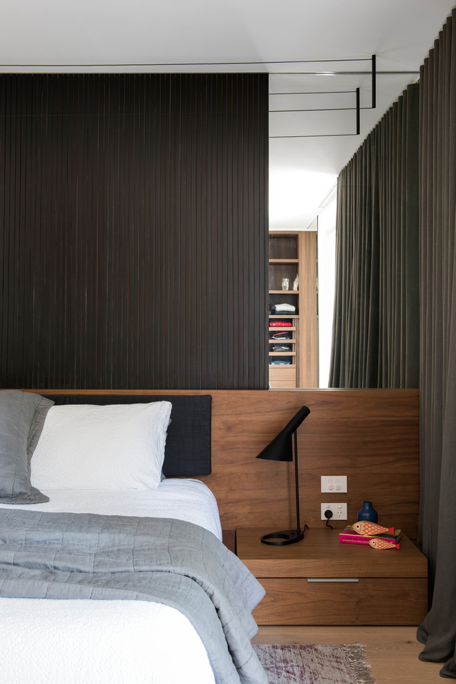 This is an example of a mid-sized modern master bedroom in Sydney with white walls and light hardwood floors.