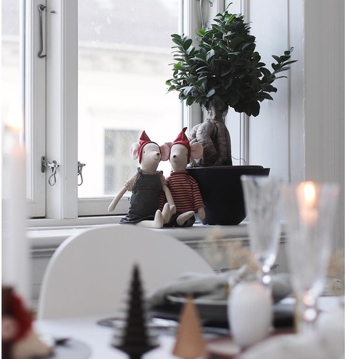 Christmas-themed fabric mice with red hats seated around a festive table with tiny desserts.