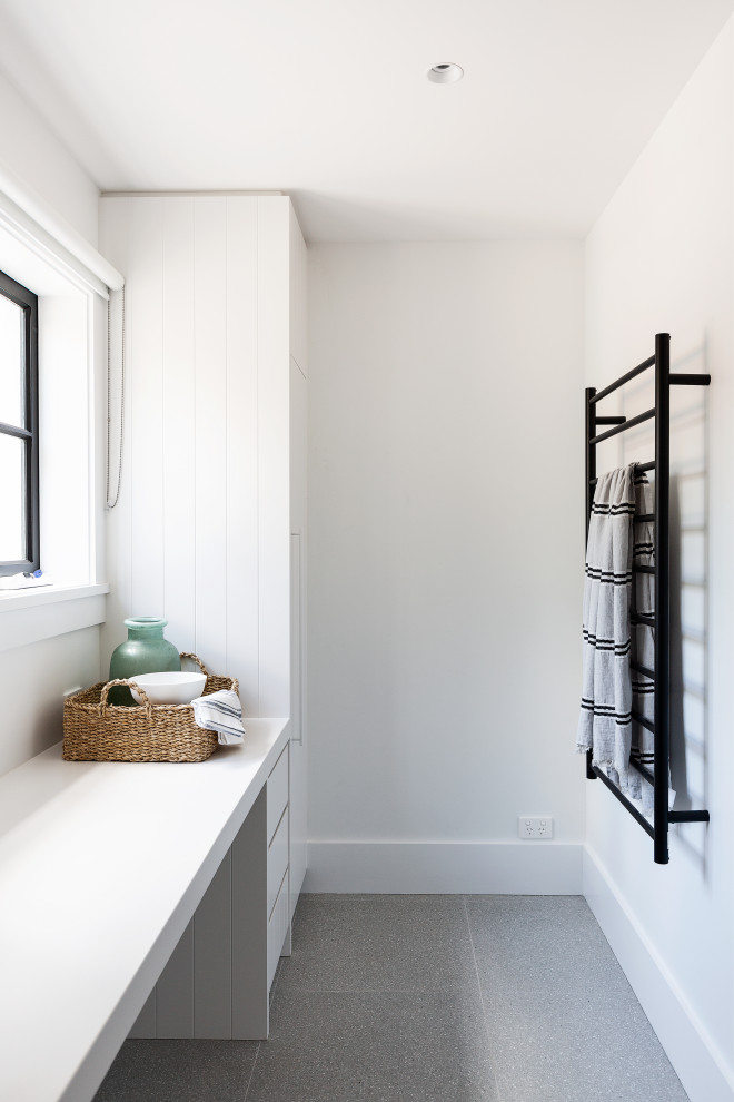 Exempel på en stor klassisk vita u-formad vitt tvättstuga enbart för tvätt, med en undermonterad diskho, släta luckor, vita skåp, bänkskiva i kvarts, vitt stänkskydd, stänkskydd i tunnelbanekakel, vita väggar, en tvättmaskin och torktumlare bredvid varandra och grått golv