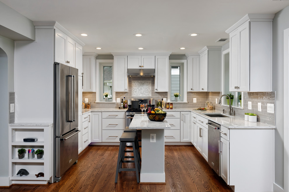 Inspiration for a transitional u-shaped kitchen in DC Metro with recessed-panel cabinets, white cabinets, with island, white benchtop, an undermount sink, grey splashback, stainless steel appliances, dark hardwood floors and brown floor.