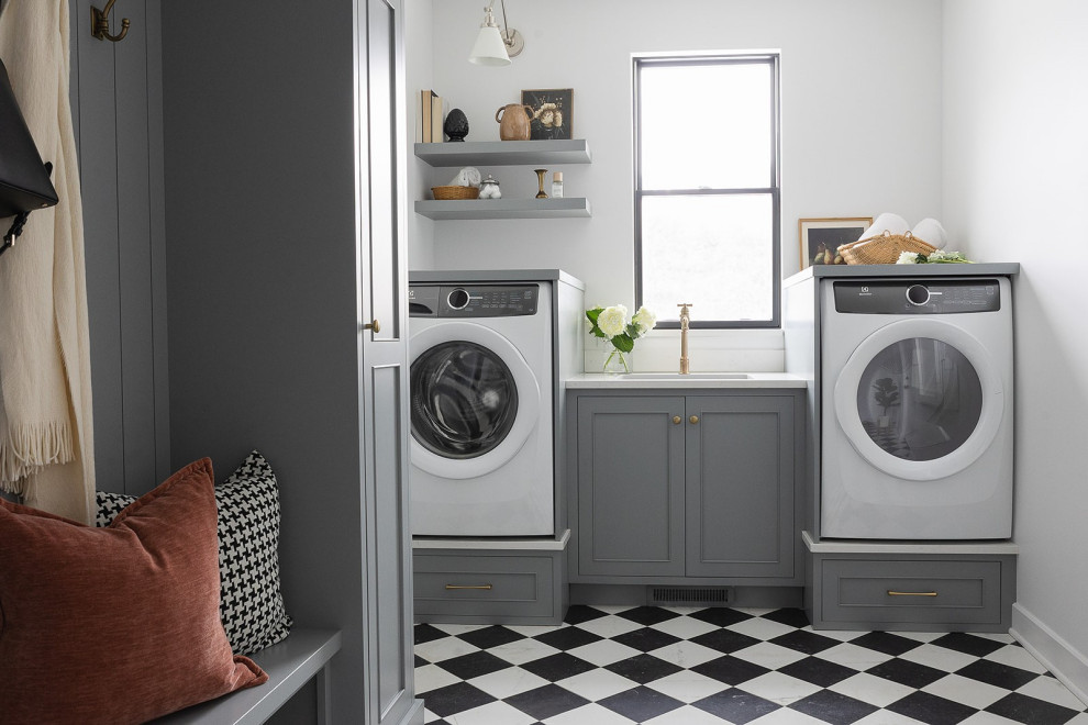 Large transitional porcelain tile laundry room photo in Other with an undermount sink, gray cabinets, quartz countertops, white backsplash, quartz backsplash, white walls, an integrated washer/dryer and white countertops