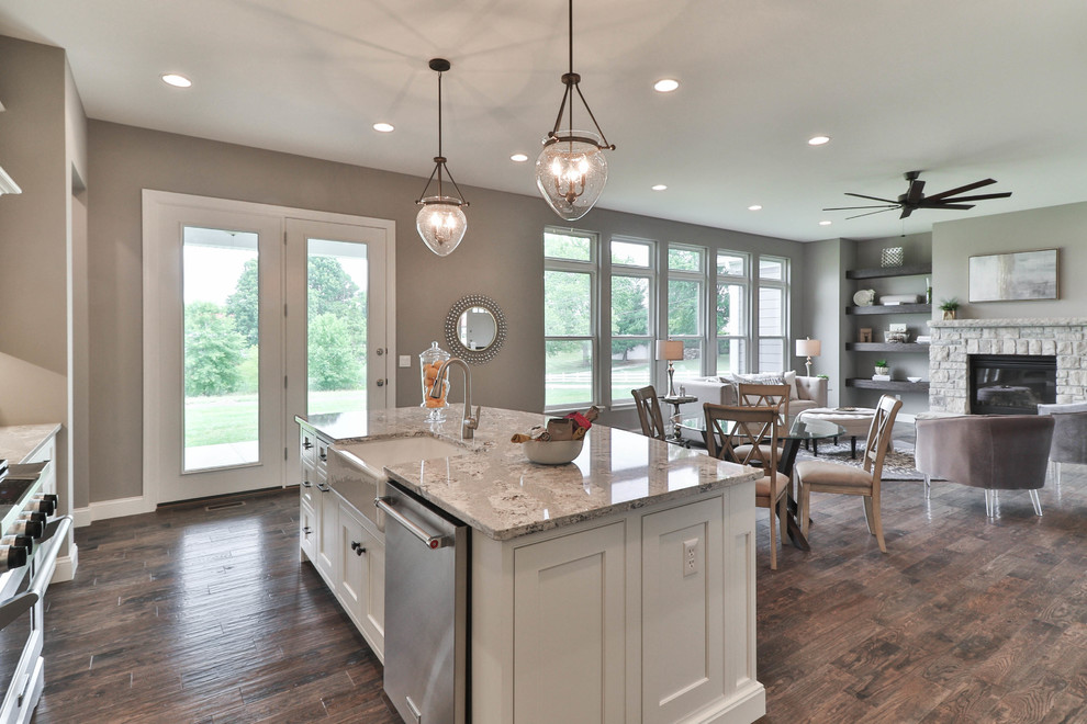 Mid-sized transitional l-shaped dark wood floor and brown floor open concept kitchen photo in St Louis with a farmhouse sink, shaker cabinets, white cabinets, granite countertops, gray backsplash, stainless steel appliances and an island