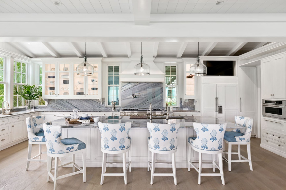 Inspiration for a large beach style galley eat-in kitchen in Tampa with an undermount sink, glass-front cabinets, white cabinets, quartzite benchtops, blue splashback, stone slab splashback, stainless steel appliances, medium hardwood floors, with island, grey floor and blue benchtop.