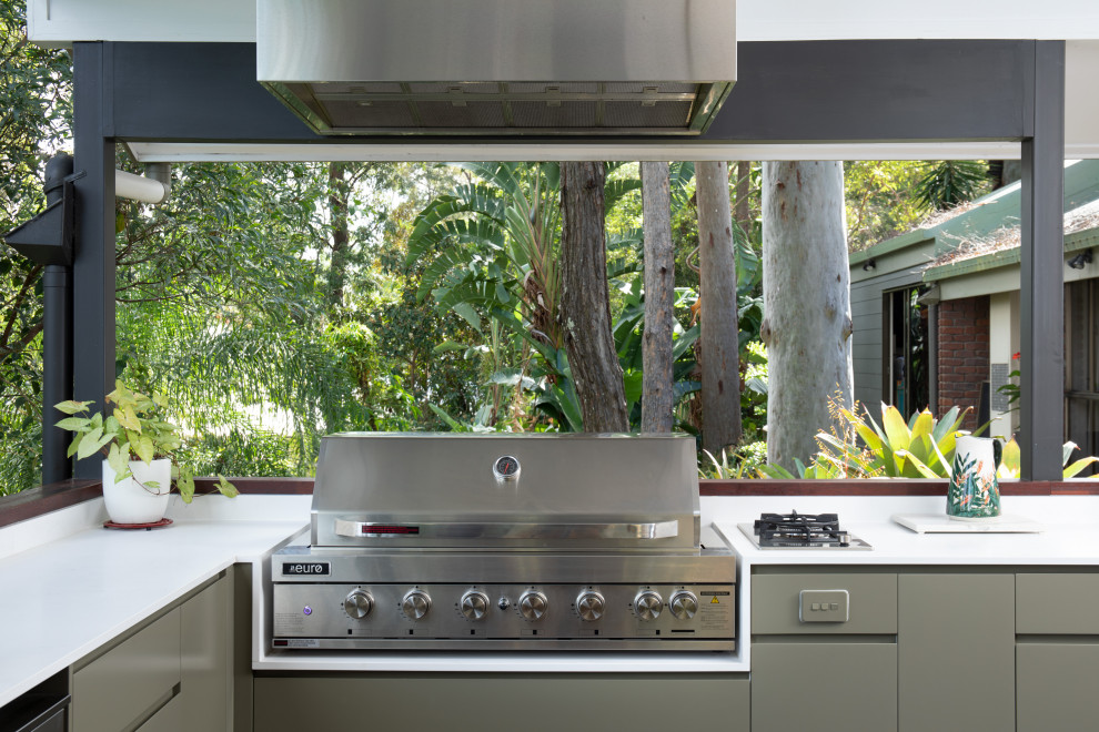 This is an example of a mid-sized modern backyard and first floor deck in Brisbane with an outdoor kitchen, a roof extension and mixed railing.