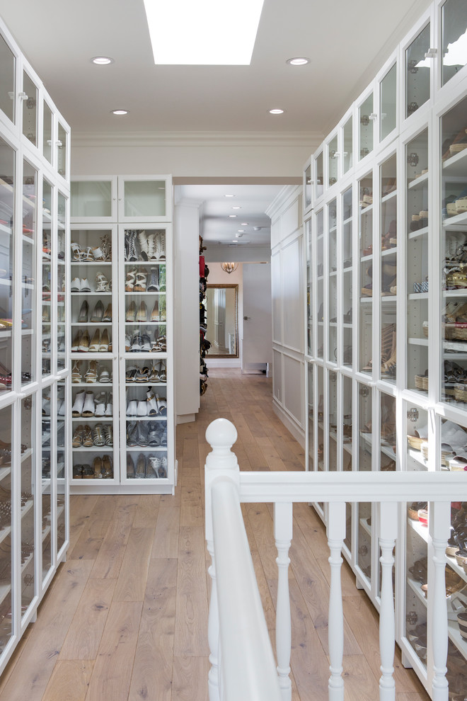 Walk-in closet - coastal women's medium tone wood floor and brown floor walk-in closet idea in Los Angeles with glass-front cabinets and white cabinets