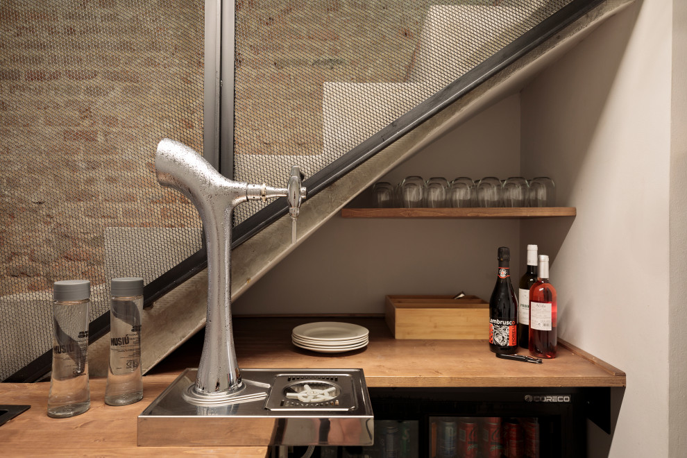 Imagen de bar en casa con barra de bar lineal de tamaño medio con fregadero encastrado, armarios con paneles lisos, puertas de armario de madera en tonos medios, encimera de madera, salpicadero negro, salpicadero de metal, suelo de cemento, suelo gris y encimeras marrones