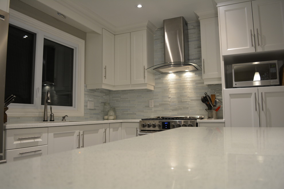 Inspiration for a mid-sized transitional l-shaped porcelain tile eat-in kitchen remodel in Toronto with an undermount sink, shaker cabinets, white cabinets, quartzite countertops, stainless steel appliances, an island, gray backsplash and matchstick tile backsplash