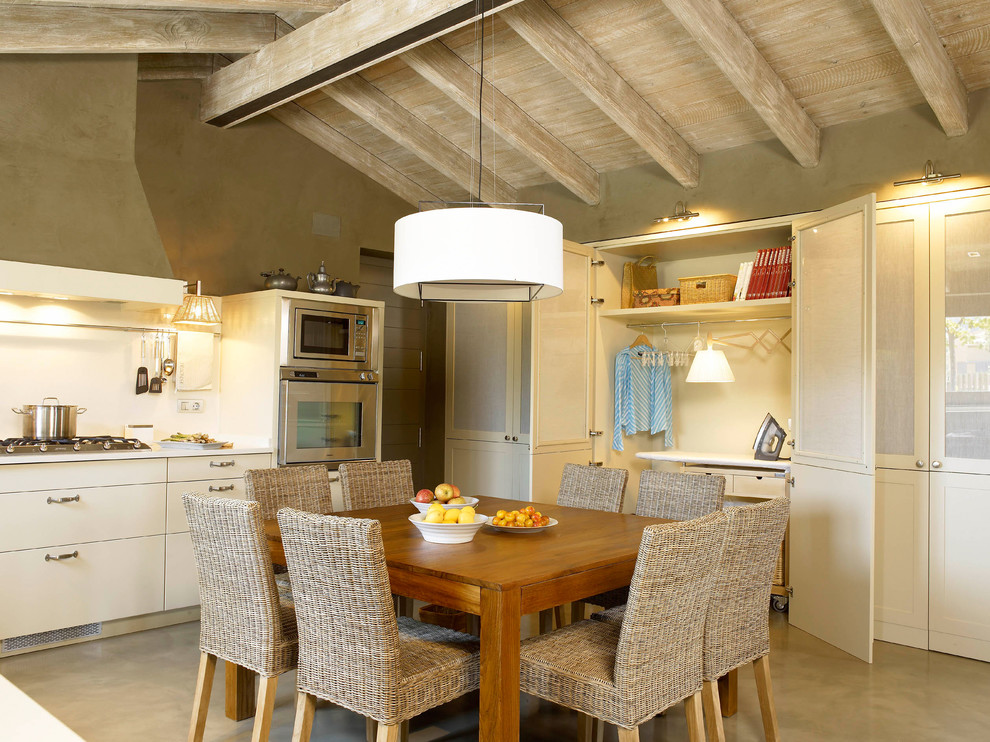 Country eat-in kitchen in Barcelona with a double-bowl sink, flat-panel cabinets, white cabinets, white splashback, stainless steel appliances, concrete floors and no island.