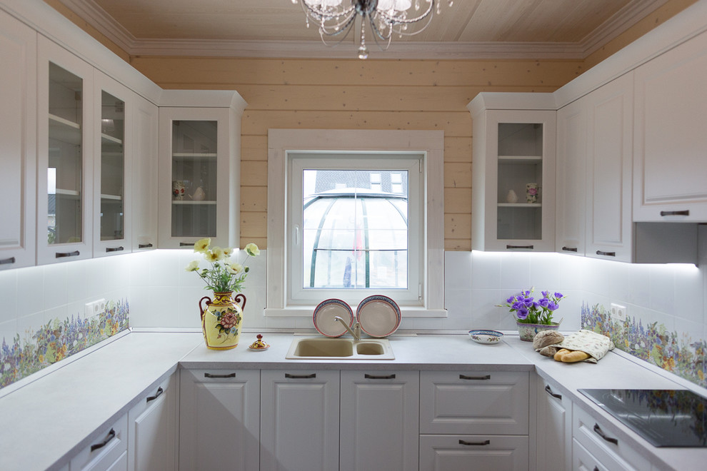 Traditional u-shaped kitchen in Moscow with a drop-in sink, raised-panel cabinets and white cabinets.