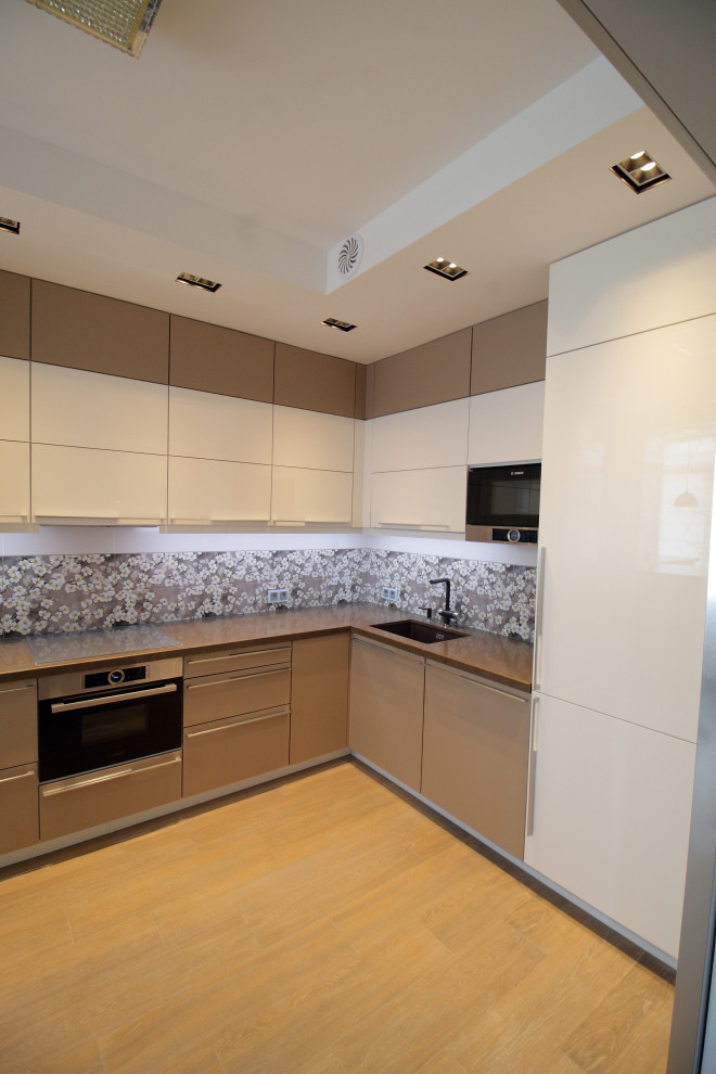 Inspiration for a large contemporary l-shaped separate kitchen in Moscow with an integrated sink, flat-panel cabinets, beige cabinets, solid surface benchtops, multi-coloured splashback, stainless steel appliances, medium hardwood floors, a peninsula, brown benchtop and recessed.