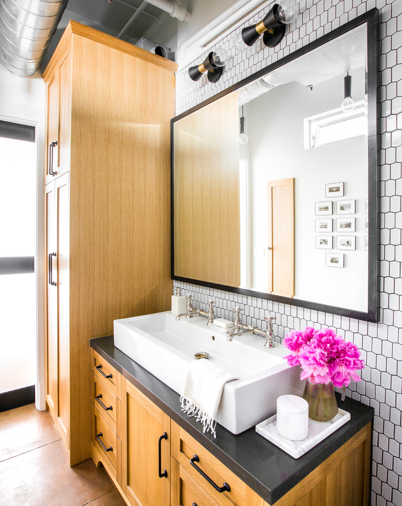 Transitional bathroom in Los Angeles with shaker cabinets, medium wood cabinets, white tile, white walls, a trough sink, brown floor and black benchtops.
