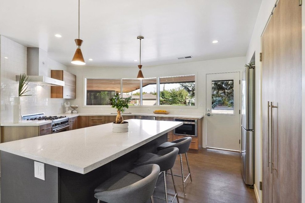 Mid-sized midcentury u-shaped eat-in kitchen in San Francisco with an undermount sink, flat-panel cabinets, medium wood cabinets, terrazzo benchtops, white splashback, ceramic splashback, stainless steel appliances, light hardwood floors, with island, grey floor and white benchtop.