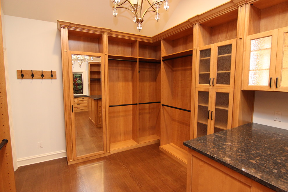 Inspiration for a large traditional walk-in wardrobe in Other with glass-front cabinets and medium wood cabinets.