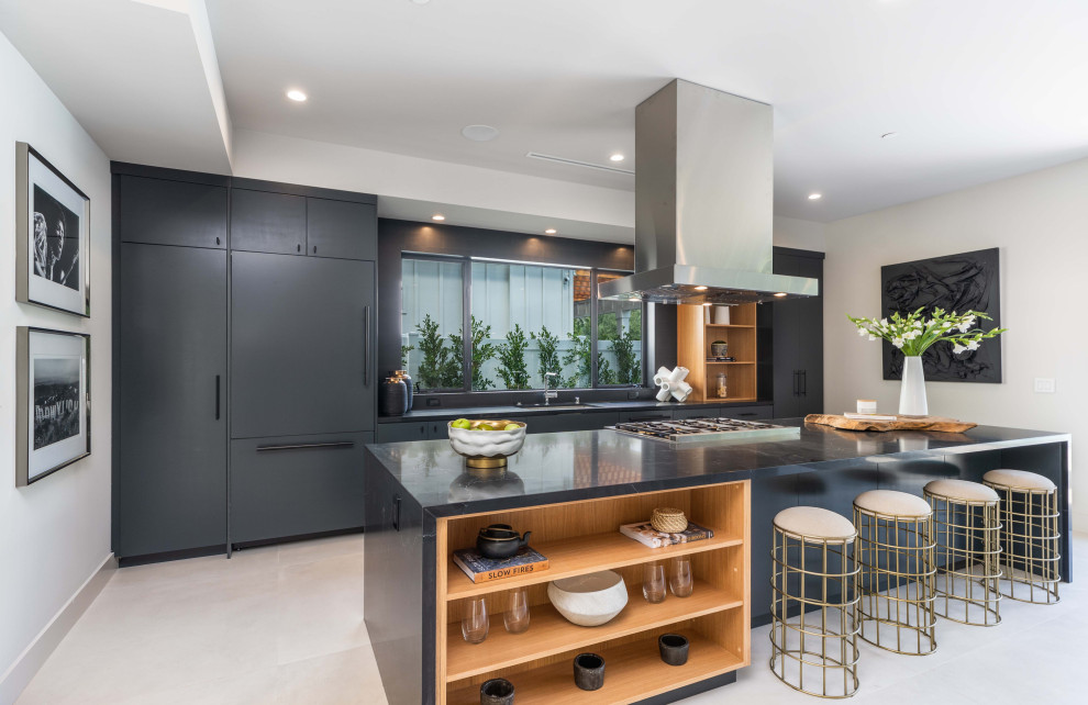 Design ideas for a large contemporary single-wall open plan kitchen in Los Angeles with a submerged sink, flat-panel cabinets, black cabinets, engineered stone countertops, integrated appliances, porcelain flooring, an island, grey floors, black worktops and a drop ceiling.
