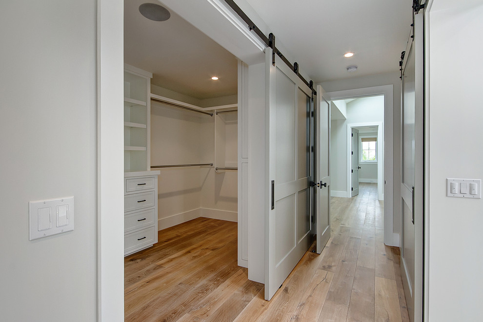 Design ideas for a mid-sized traditional walk-in wardrobe in Orange County with white cabinets, medium hardwood floors and brown floor.
