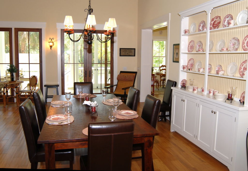 This is an example of a mid-sized country open plan dining in Atlanta with yellow walls, medium hardwood floors, no fireplace and brown floor.
