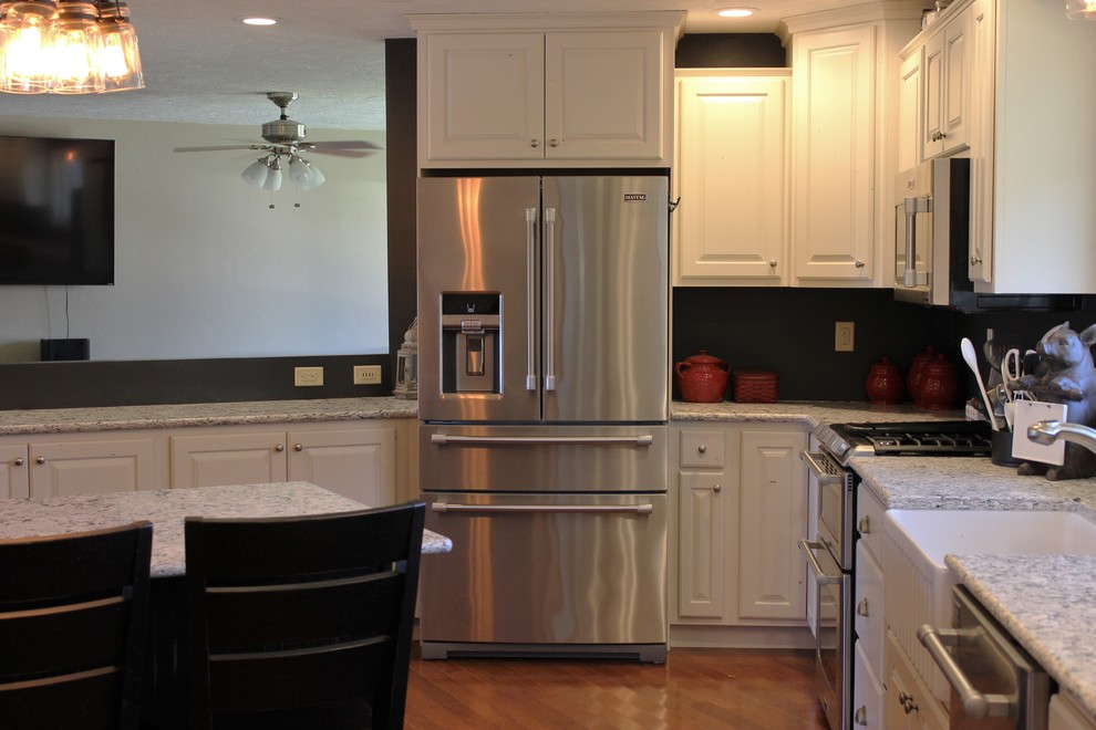 Example of a large mountain style l-shaped light wood floor open concept kitchen design in Chicago with a farmhouse sink, raised-panel cabinets, white cabinets, quartz countertops, stainless steel appliances and an island