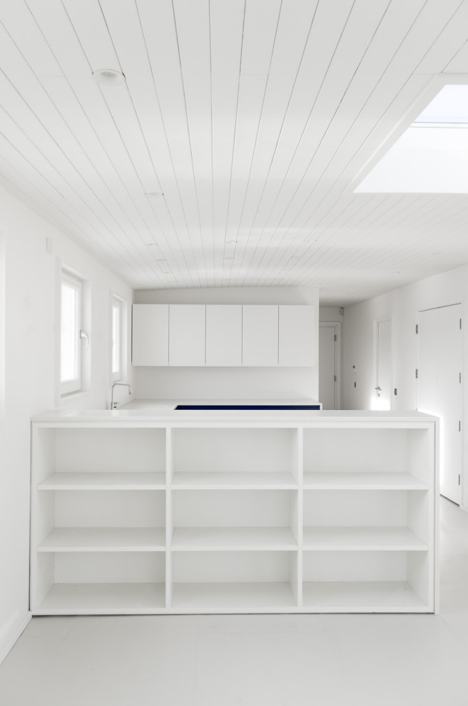Idéer för att renovera ett mellanstort maritimt vit vitt kök, med en integrerad diskho, släta luckor, vita skåp, bänkskiva i koppar, vitt stänkskydd, svarta vitvaror, en köksö och vitt golv