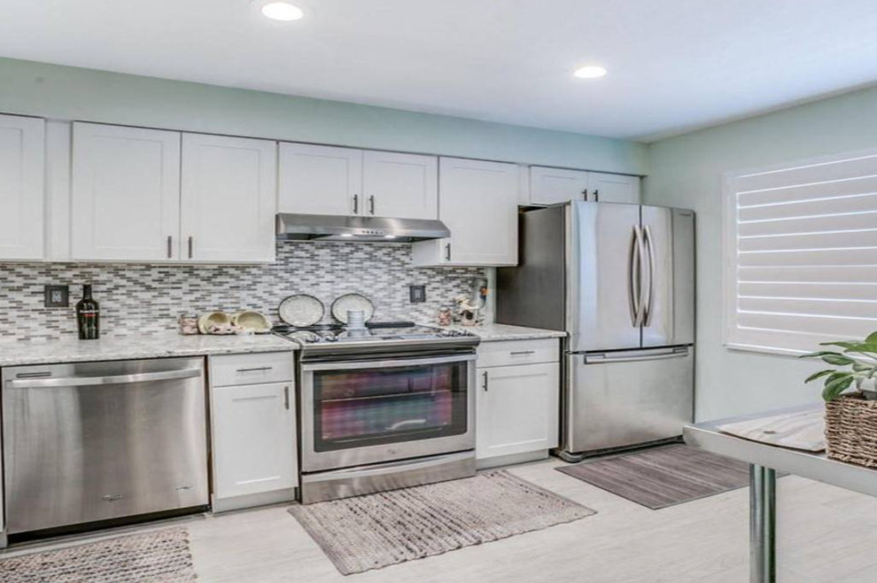 Enclosed kitchen - mid-sized transitional l-shaped porcelain tile and beige floor enclosed kitchen idea in Houston with shaker cabinets, white cabinets, granite countertops, multicolored backsplash, mosaic tile backsplash, stainless steel appliances, no island and white countertops
