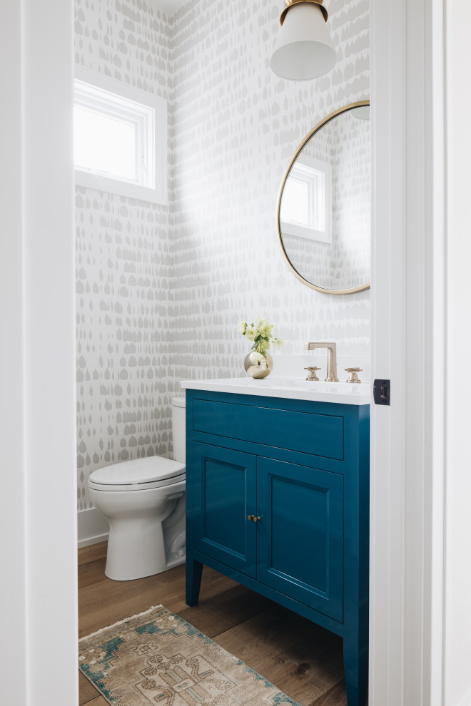 Powder Room - Inspiration for a small coastal light wood floor and wallpaper powder room remodel in Grand Rapids with shaker cabinets, blue cabinets, white countertops and a freestanding vanity