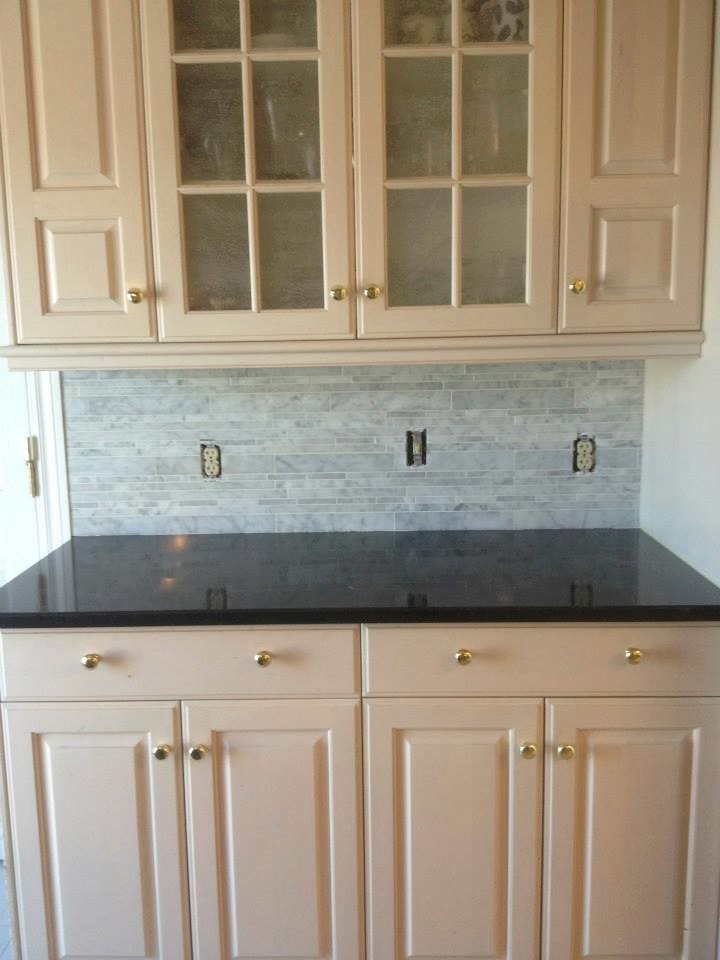 Mid-sized single-wall open concept kitchen photo with raised-panel cabinets, white cabinets, onyx countertops, gray backsplash and matchstick tile backsplash