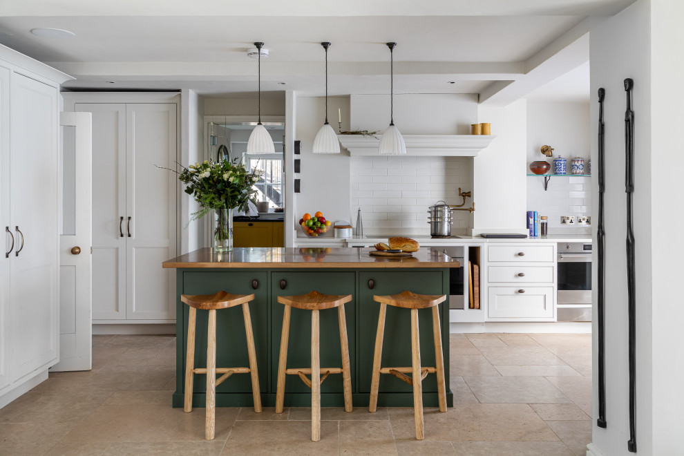 Inspiration for a country galley kitchen in Oxfordshire with beaded cabinets, white cabinets, stainless steel appliances, an island, beige floors and white worktops.