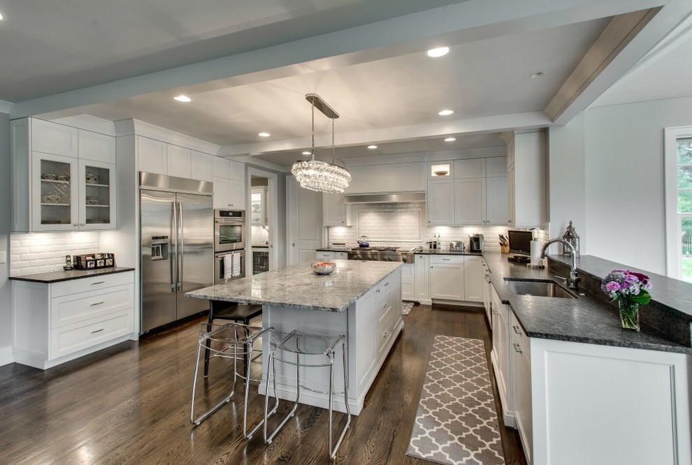Example of a transitional u-shaped dark wood floor open concept kitchen design in Chicago with an undermount sink, white cabinets, granite countertops, white backsplash, subway tile backsplash, stainless steel appliances and an island
