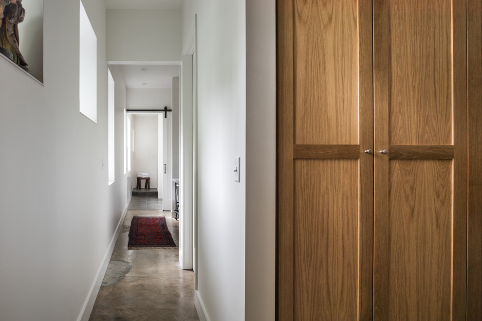This is an example of a mid-sized industrial gender-neutral walk-in wardrobe in Houston with shaker cabinets, medium wood cabinets and concrete floors.