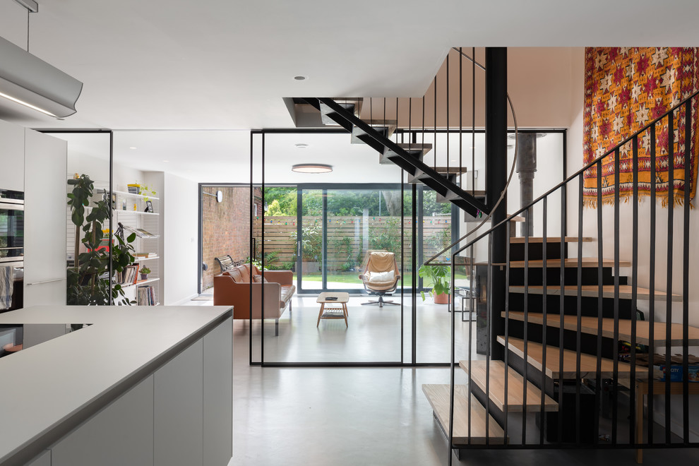 This is an example of a mid-sized modern wood curved staircase in Manchester with metal risers and metal railing.
