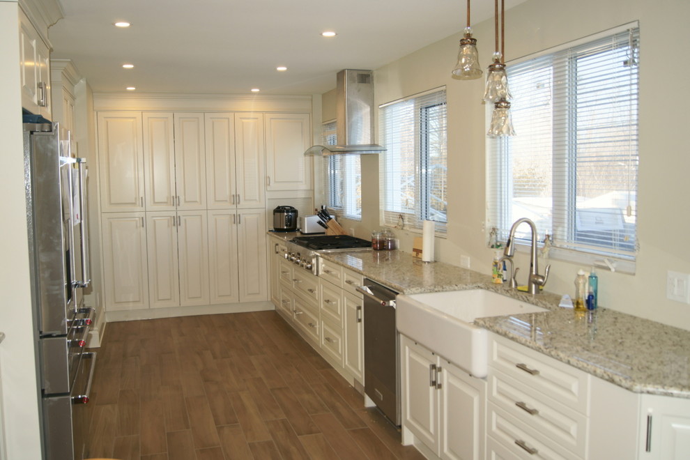 Inspiration for a mid-sized transitional galley medium tone wood floor open concept kitchen remodel in Ottawa with a farmhouse sink, raised-panel cabinets, white cabinets, granite countertops and stainless steel appliances
