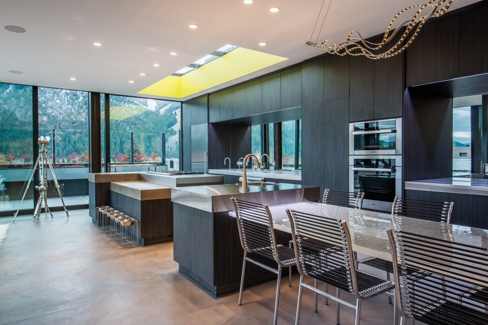 This is an example of a contemporary galley kitchen in Other with an integrated sink, flat-panel cabinets, dark wood cabinets, stainless steel benchtops, stainless steel appliances, concrete floors and multiple islands.