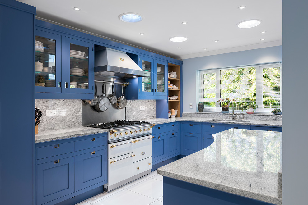 Mid-sized contemporary l-shaped open plan kitchen in Hampshire with a drop-in sink, shaker cabinets, blue cabinets, granite benchtops, grey splashback, marble splashback, white appliances, ceramic floors, with island, white floor and grey benchtop.