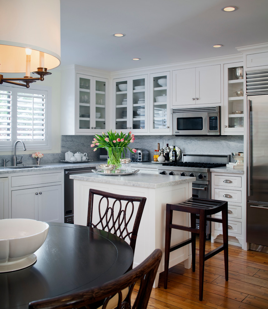 Inspiration for a small transitional l-shaped light wood floor eat-in kitchen remodel in Los Angeles with an undermount sink, recessed-panel cabinets, white cabinets, marble countertops, stone slab backsplash, stainless steel appliances, an island and gray backsplash
