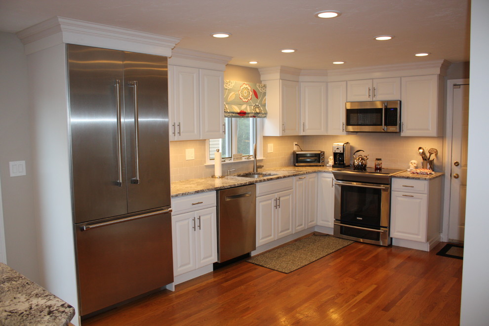 Inspiration for a large transitional l-shaped light wood floor eat-in kitchen remodel in Boston with an undermount sink, raised-panel cabinets, white cabinets, granite countertops, gray backsplash, ceramic backsplash, stainless steel appliances and an island