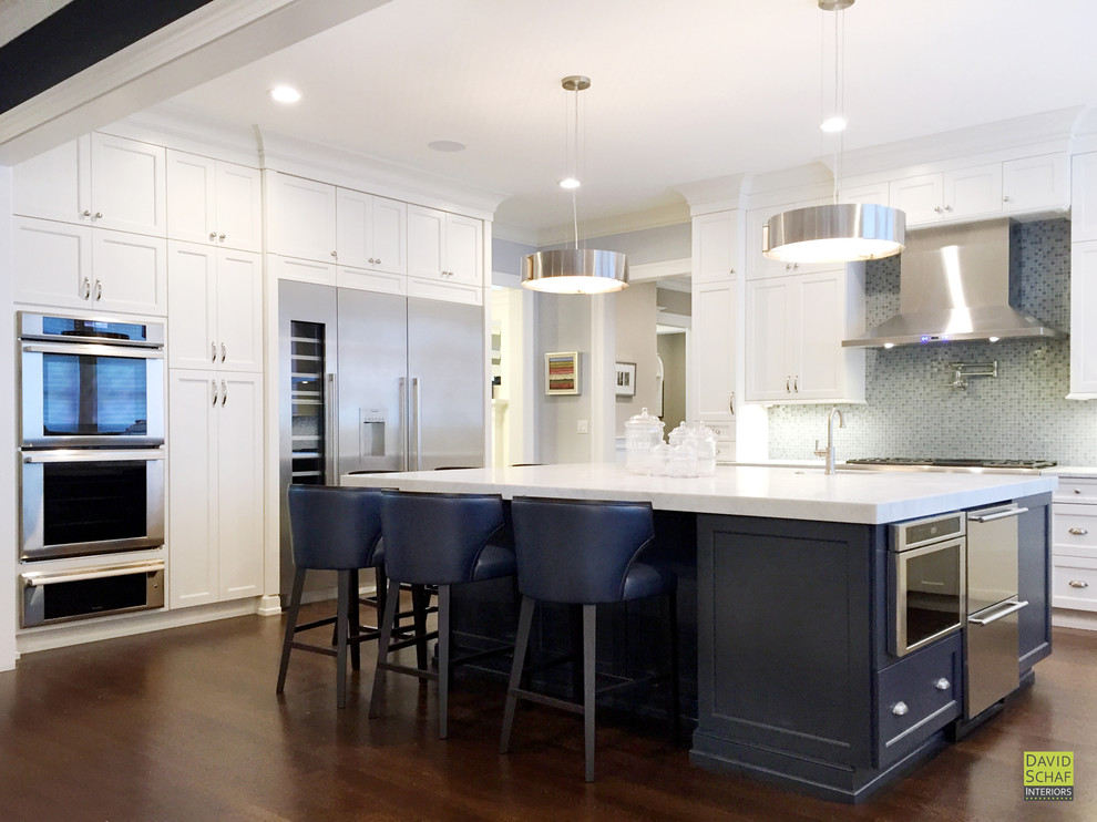 Large transitional u-shaped dark wood floor and brown floor kitchen photo in New York with an undermount sink, recessed-panel cabinets, white cabinets, marble countertops, gray backsplash, mosaic tile backsplash, stainless steel appliances, an island and white countertops
