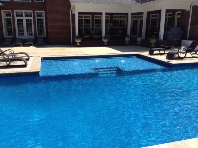 Inspiration for a large traditional backyard custom-shaped pool in Birmingham with natural stone pavers.