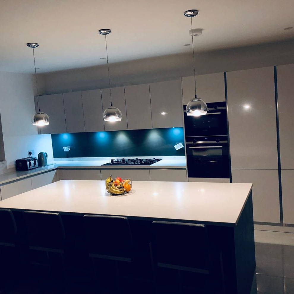Design ideas for a mid-sized modern l-shaped separate kitchen in London with beige cabinets, quartzite benchtops, blue splashback, limestone splashback, black appliances, ceramic floors, with island, white floor, white benchtop and recessed.