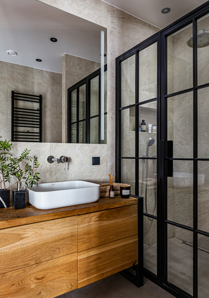 Photo of a small industrial 3/4 bathroom in Saint Petersburg with flat-panel cabinets, medium wood cabinets, an alcove shower, beige tile, porcelain tile, beige walls, porcelain floors, a drop-in sink, wood benchtops, beige floor, a hinged shower door, brown benchtops, a single vanity and a freestanding vanity.