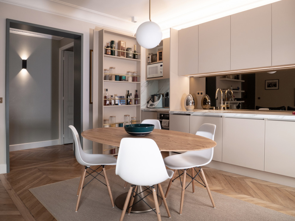Photo of a mid-sized transitional single-wall open plan kitchen in Paris with an integrated sink, beaded inset cabinets, beige cabinets, marble benchtops, mirror splashback, panelled appliances, no island, beige benchtop, metallic splashback and light hardwood floors.