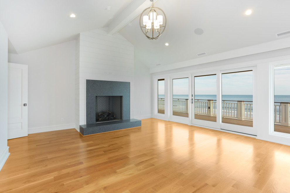 ウィルミントンにある広いビーチスタイルのおしゃれな主寝室 (グレーの壁、淡色無垢フローリング、標準型暖炉、塗装板張りの暖炉まわり、三角天井) のインテリア