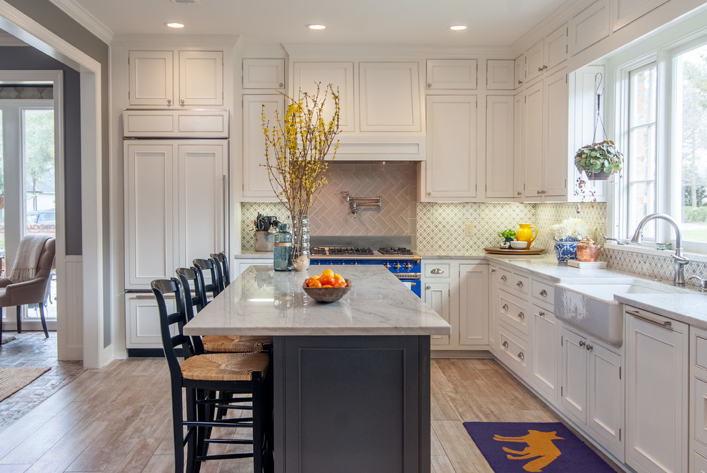 Photo of a large transitional l-shaped kitchen pantry in New Orleans with quartz benchtops, porcelain floors, with island, flat-panel cabinets, white cabinets, white splashback, a farmhouse sink, cement tile splashback, coloured appliances, grey floor and white benchtop.