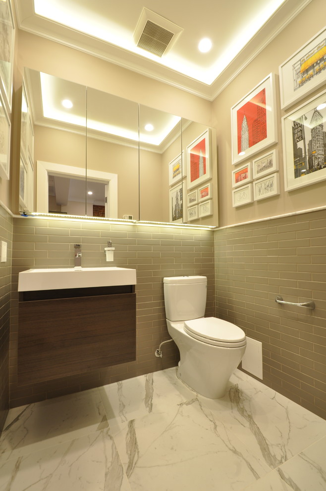 Design ideas for a small modern powder room in New York with flat-panel cabinets, dark wood cabinets, a two-piece toilet, beige tile, beige walls, marble floors and an integrated sink.