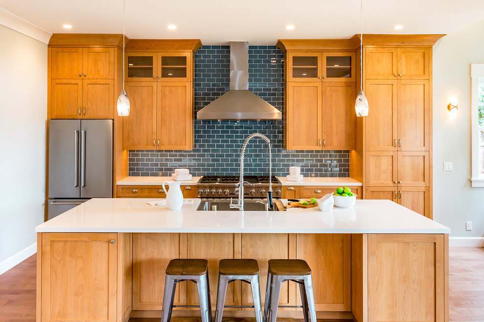 Inspiration for an arts and crafts u-shaped eat-in kitchen in San Francisco with a drop-in sink, shaker cabinets, light wood cabinets, blue splashback, subway tile splashback, stainless steel appliances, light hardwood floors and with island.