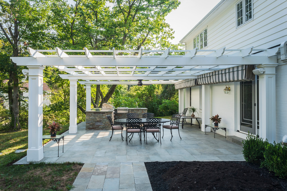 Mid-sized traditional backyard patio in Other with an outdoor kitchen, natural stone pavers and a pergola.
